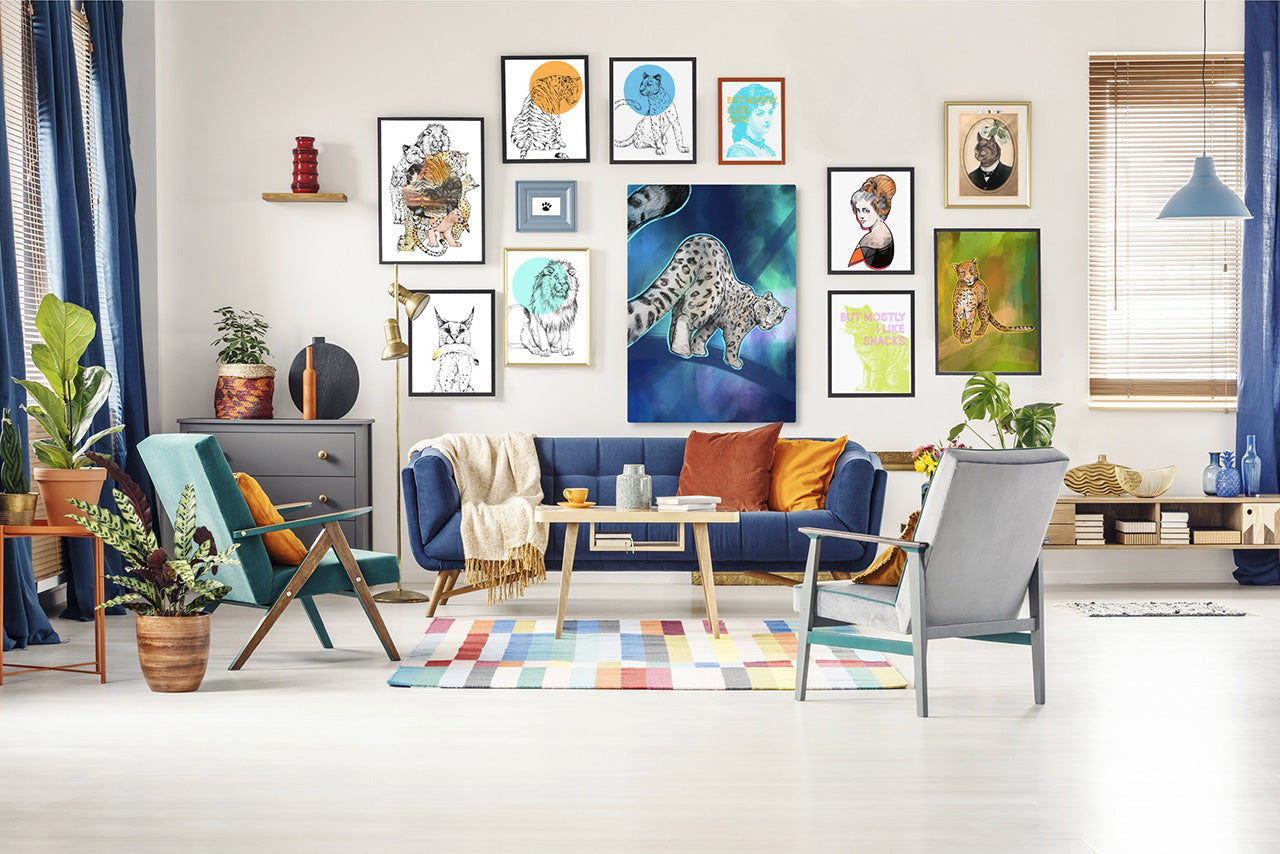 Living room with colorful decor, blue sofa, and various framed animal and portrait artworks on the wall. Room features plants, colorful rug, and modern furniture.