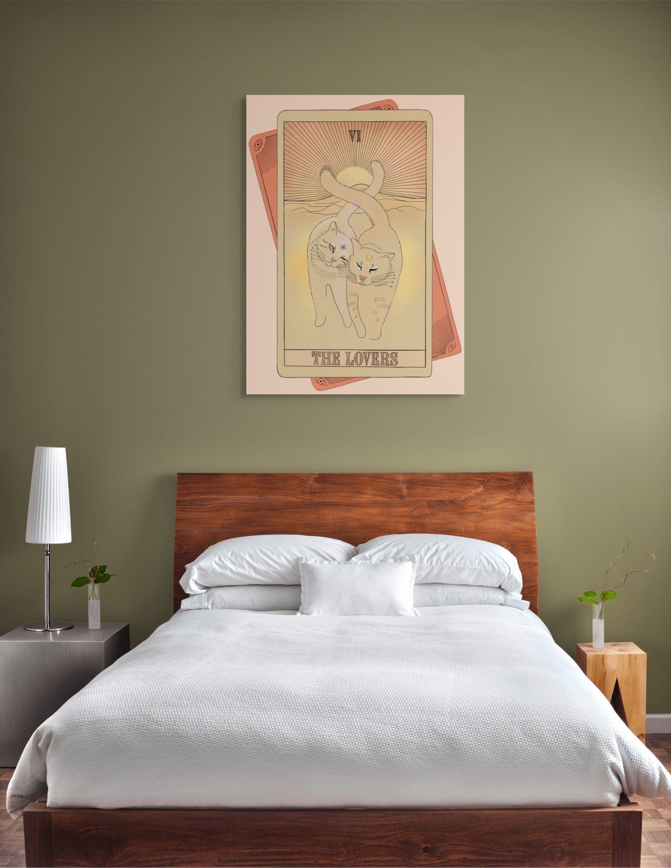 A modern bedroom with a wooden bed, white bedding, green walls, and a large artwork above the bed featuring cats illustrated as "The Lovers" tarot card.