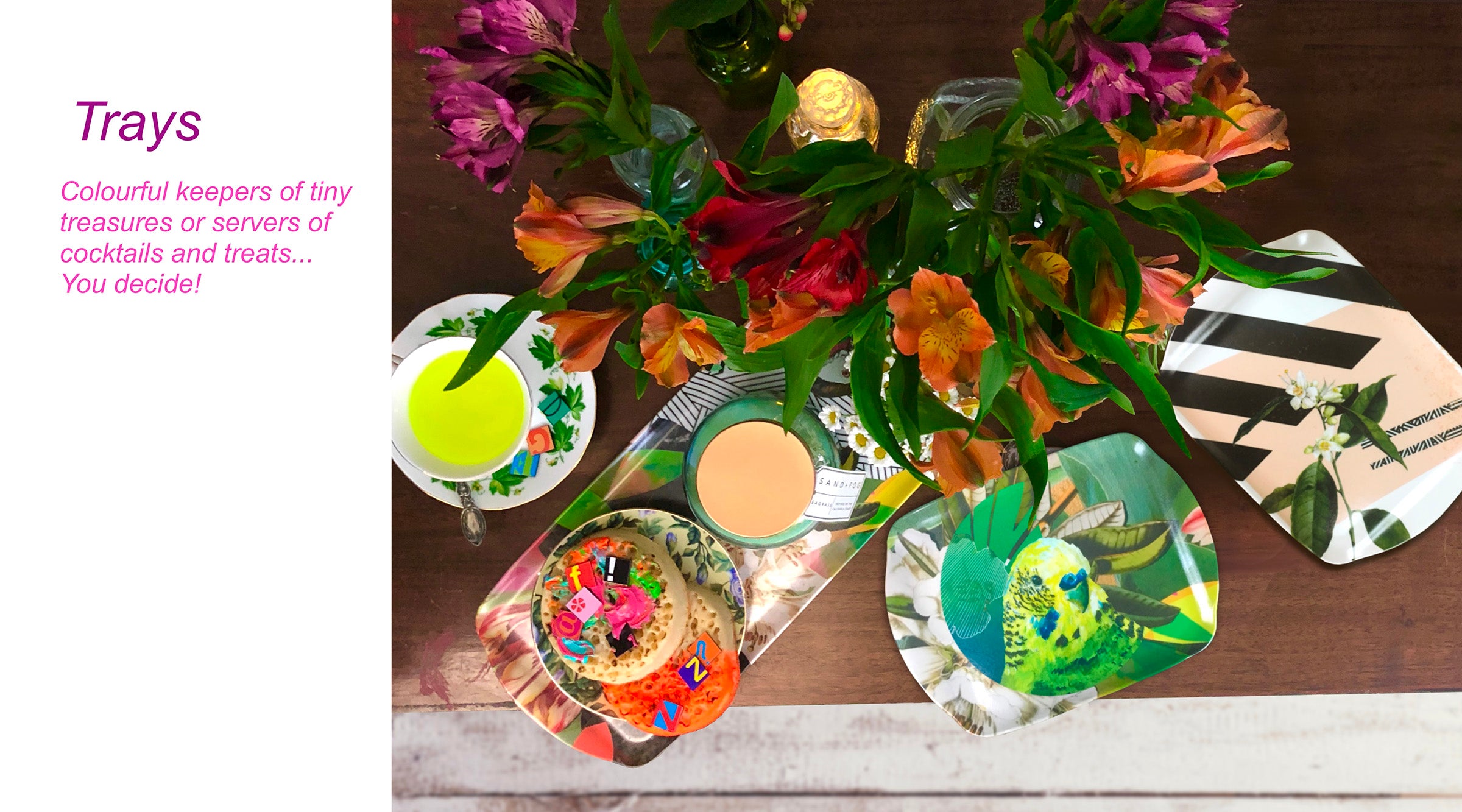 Decorative trays with vibrant patterns holding a variety of items, including flowers, a drink, and small plates, set on a wooden table.