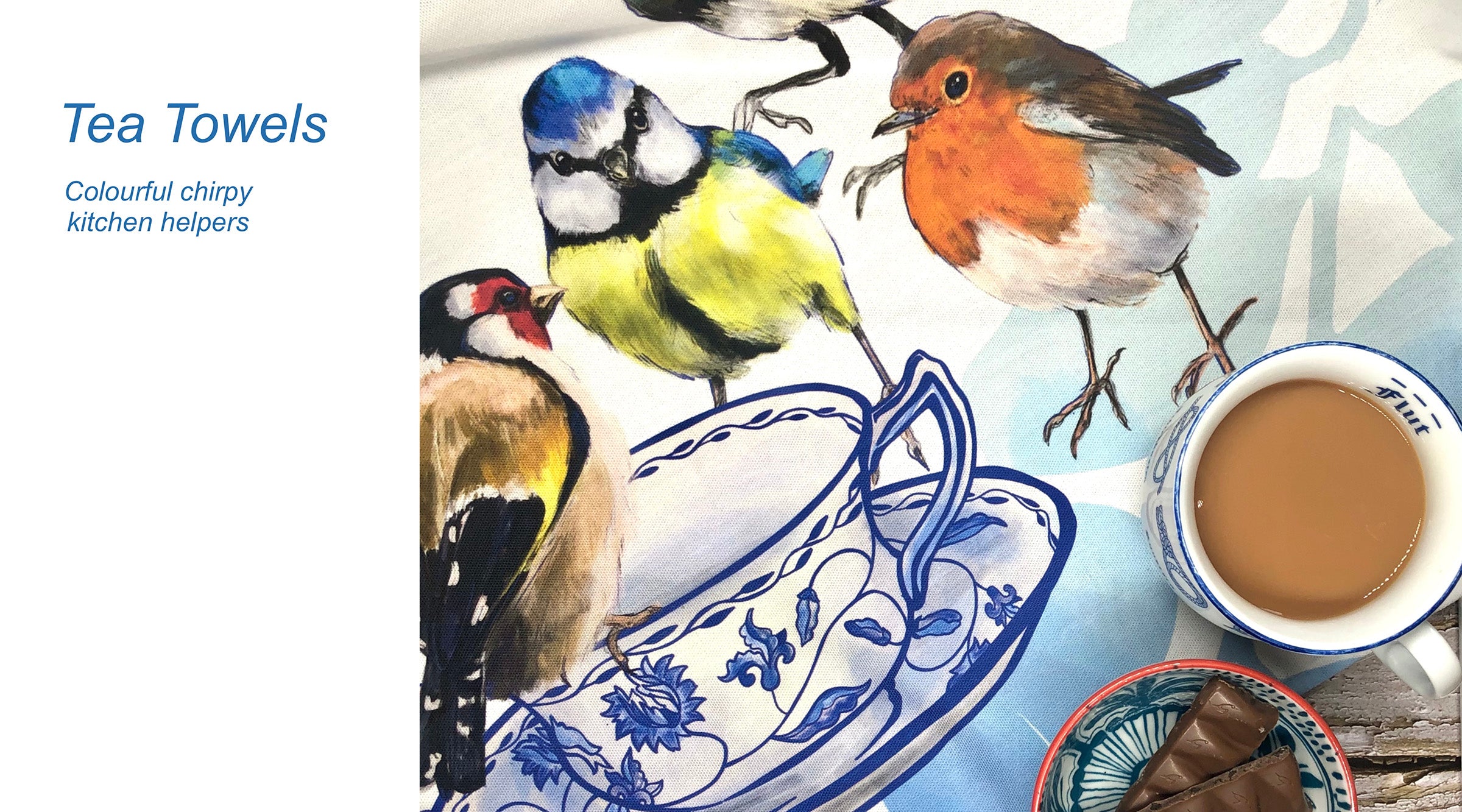 A tea towel with illustrations of three birds around a blue and white teacup, next to a mug of tea and a plate with pieces of chocolate.