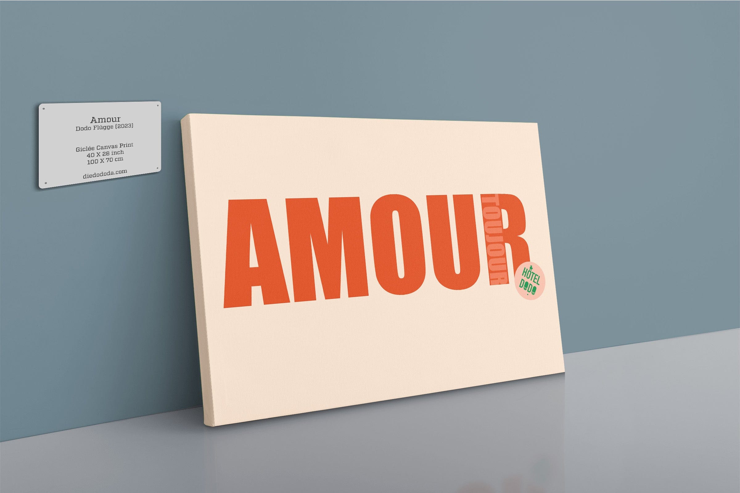 The Shromps Amour Matte Canvas Print features "AMOUR" in bold orange letters and is displayed against a blue wall next to a gallery plaque detailing artist information.