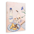 A kitten reaches for pastries on a plate beside a bottle of milk and a box labeled "Katzenzungen," the German word for "cats tongues." The scene is beautifully captured in the Hôtel Dodo Katzenzungen Giclée Canvas Print, featuring a blue flower and other small decorative items in the background.