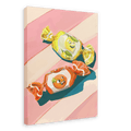 The Pillow Sweets Citrus Giclée Canvas Print by Hôtel Dodo features a delightful painting of two smiling candy wrappers, one yellow with a zesty lemon and the other red with a tomato, set against a pink and white striped background.