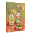 The Hôtel Dodo Olives Olé Canvas Print showcases a framed painting with two cans, one labeled "Olives" adorned with a straw and flower, the other labeled "Gordal Picante" holding flowers, accompanied by a bowl of olives on a polka dot surface that evokes Hôtel Dodo's cocktail garnish aesthetics.