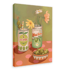 The Hôtel Dodo Olives Olé Canvas Print showcases a framed painting with two cans, one labeled "Olives" adorned with a straw and flower, the other labeled "Gordal Picante" holding flowers, accompanied by a bowl of olives on a polka dot surface that evokes Hôtel Dodo's cocktail garnish aesthetics.