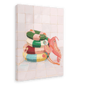 A giclée canvas print from Hôtel Dodo, featuring the Platypus Pool Pals collection, depicts a trio of vibrant, striped pool rings and a pink inflatable lobster resting on a tiled floor against a tiled wall.