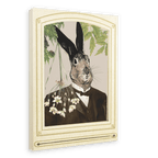 The Hare In A Suit Canvas Print by Animals In Suits features a portrait of Mister Hare, a rabbit with black-tipped ears dressed in a dark suit, posed before cascading flowers and lush greenery crafted from vintage botanical illustrations, all elegantly framed with an ornate cream border.