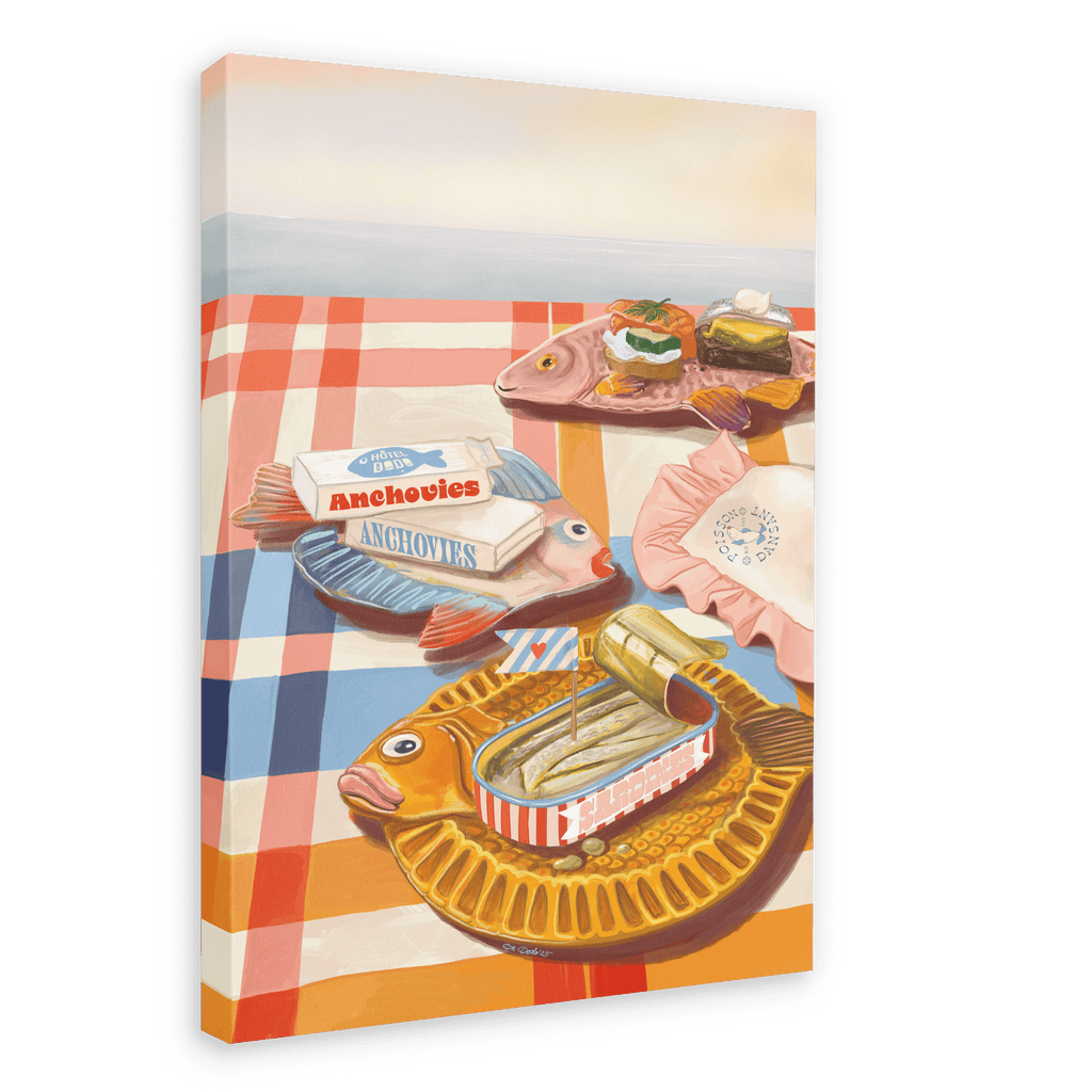 The “Dishy Fishy Giclée Canvas Print” by Hôtel Dodo depicts a picnic table adorned with retro fish plates filled with tinned fish, anchovies, and other treats on a red and white checked tablecloth by the water—perfectly capturing the charm of summer girl dinners.