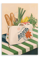 The Bodega Bounty Giclée Canvas Print by Hôtel Dodo depicts a canvas grocery bag, brimming with baguettes, leeks, carrots, bananas, and a can, resting on a striped table—while the curious face of a bodega cat peeks out from inside the bag.