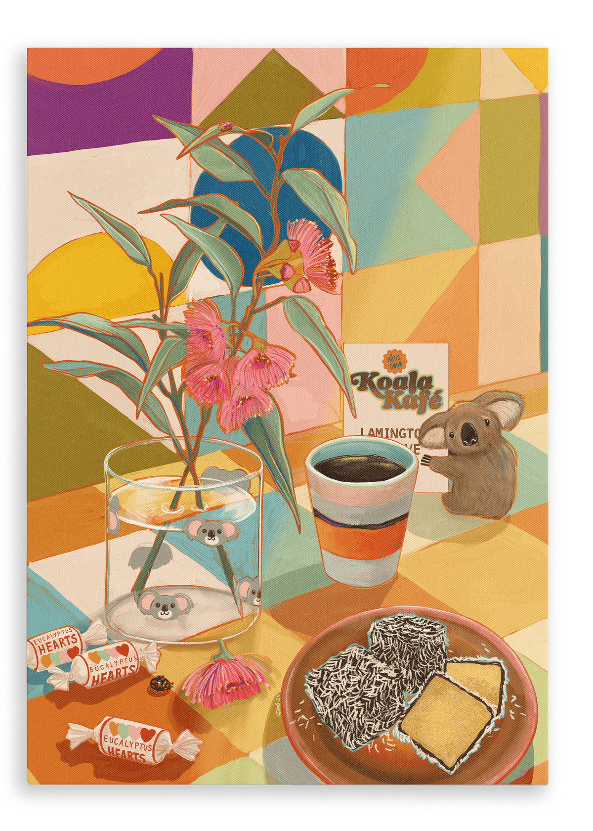 A table adorned with eucalyptus leaves, candy, a glass of water, a cup of coffee, scrumptious Lamington cake, a Koala Kafé card, and a toy koala is set against the vibrant geometric backdrop of the Hôtel Dodo “Koala Kafé” Giclée Canvas Print—radiating retro Australiana charm.