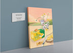 The Hôtel Dodo “Butterlicious Giclée Canvas Print” showcases a cartoon lamb, daisies, and a box of butter with retro butter curls arranged on a table alongside bread and a knife, displayed next to a label reading, “Butterlicious, Josh Tiessen (2022).”.