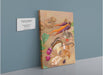 A giclée canvas print titled "Earthly Delights" from Kitsch Kanaveral features an array of vegetables, mushrooms, a mouse, and a beetle set against a muted background. It is showcased on a blue wall with an accompanying label.