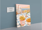 The “Frites Vites Giclée Canvas Print” by Hôtel Dodo features gourmet fries and a drink on a checkered table, set near a beach with a striped chair and serene sea in the background, accompanied by a gallery plaque.