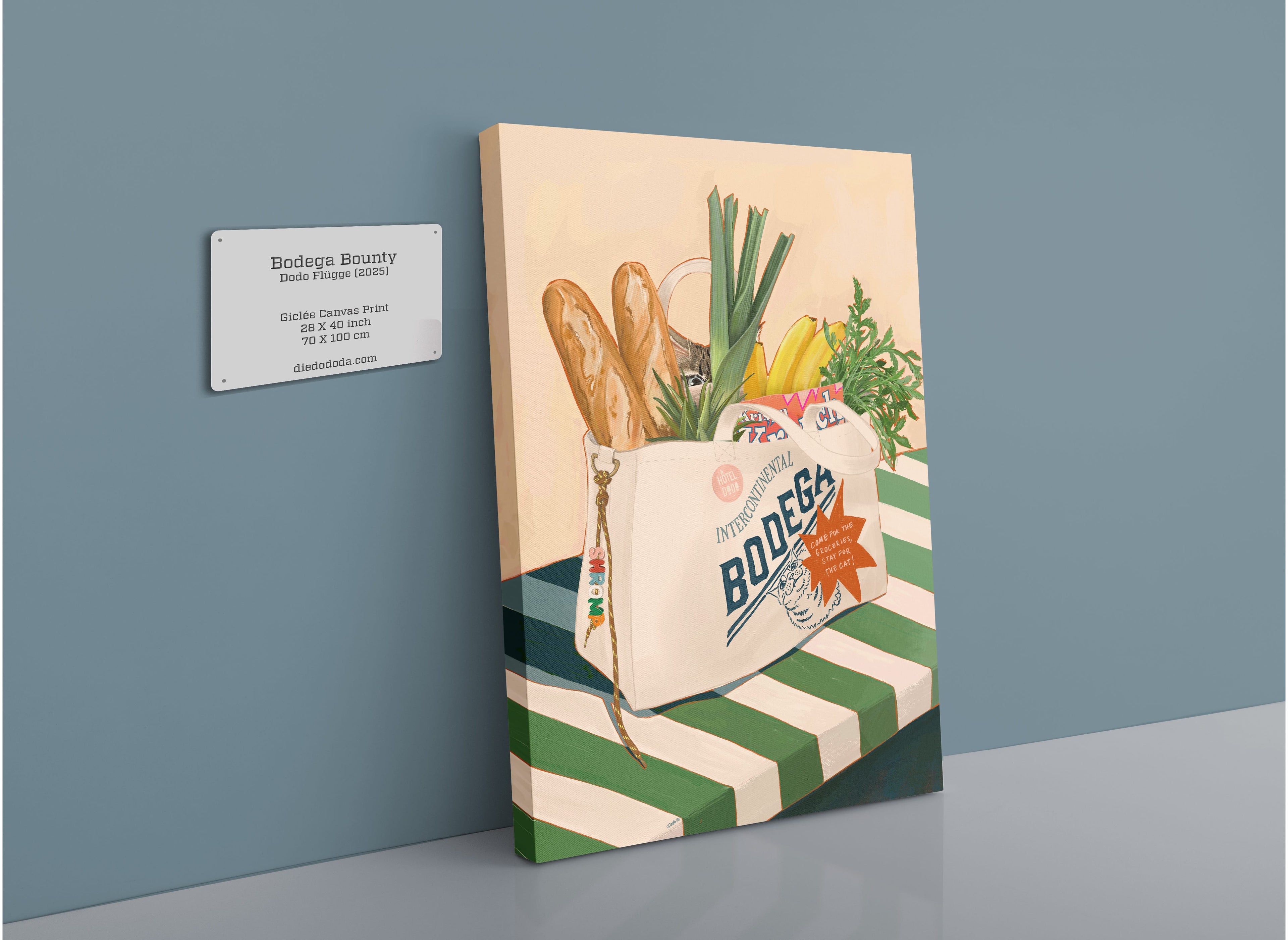 The Hôtel Dodo “Bodega Bounty” Giclée Canvas Print depicts a grocery bag brimming with baguettes and produce, resting on a green and white striped surface—a nostalgic nod to groceries freshly brought home from your neighborhood bodega. Displayed beside an artwork details wall plaque, this charming scene feels nearly complete, as if a curious bodega cat might appear at any moment to investigate the cat pouch nestled among the fresh finds.
