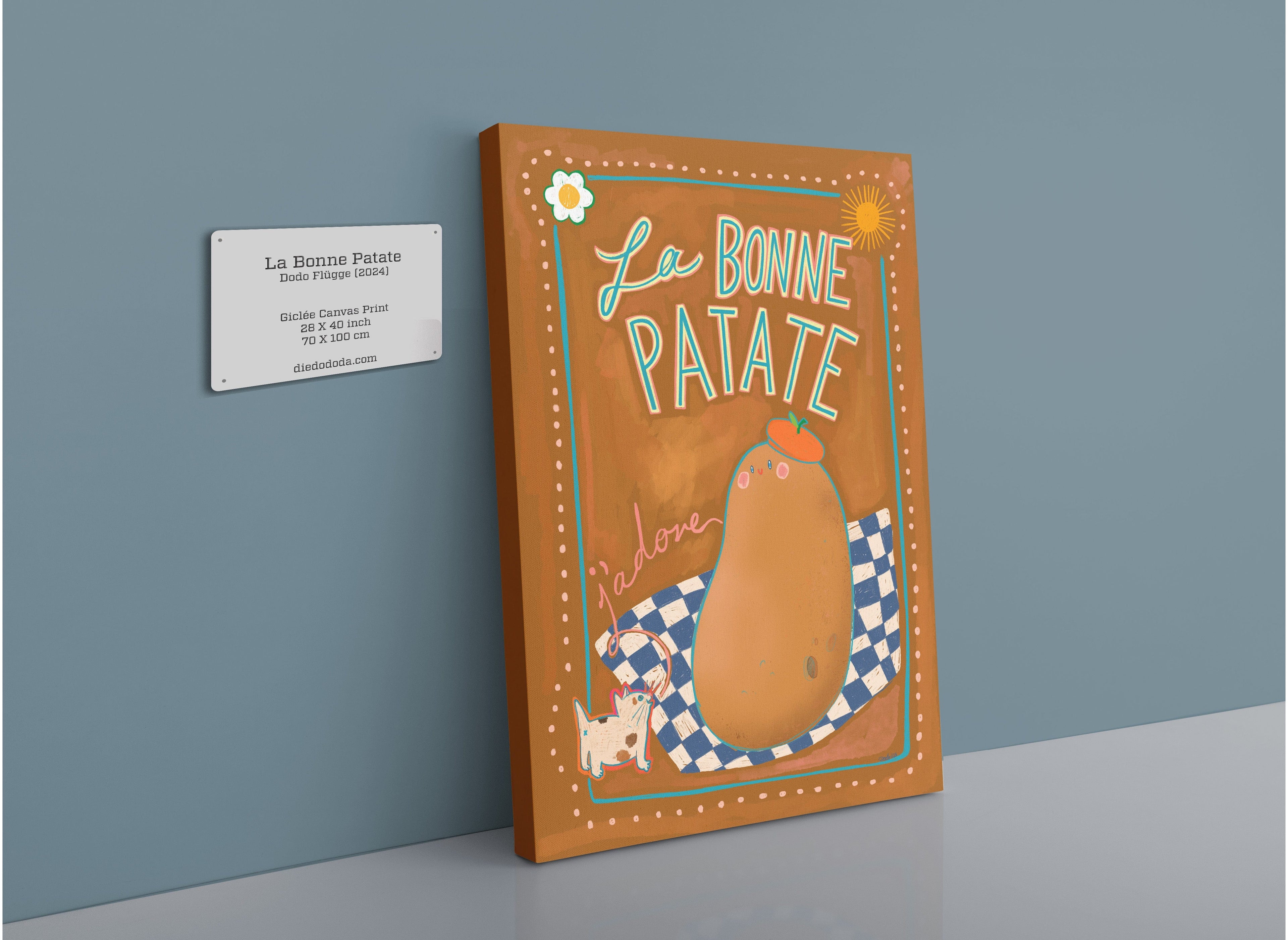 Image of a framed artwork titled "La Bonne Patate Canvas Print" by Aventures Des Créatures, featuring an illustration of a potato, a cat, and a checkered cloth. A small information plaque is displayed to the left of the product, celebrating the potato as a versatile food.