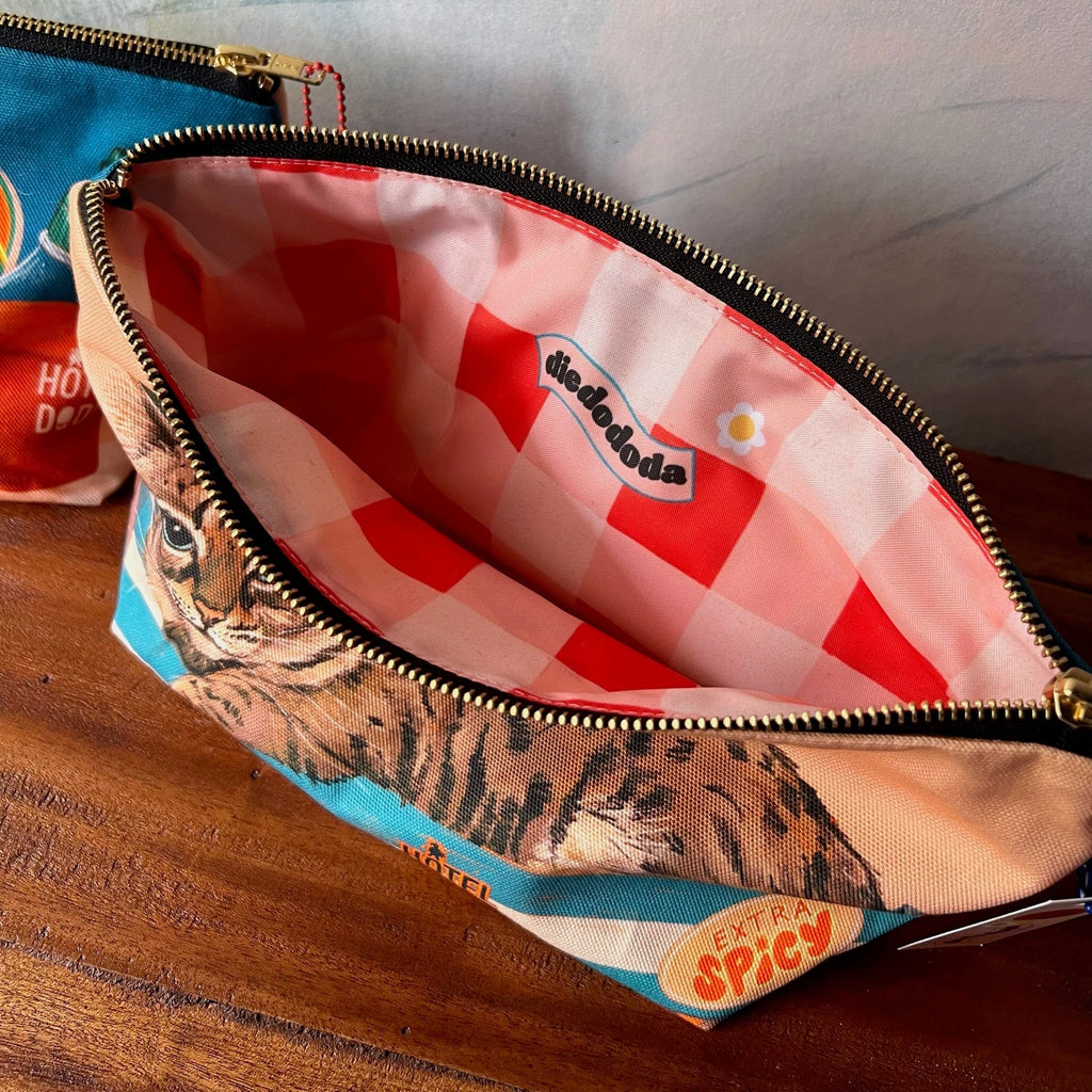 The Bodega Cat Hot Sauce Pouch by Hôtel Dodo is a handmade cotton organiser with a zippered cat design, red checkered lining, and a small "dedendoda" label inside—your perfect market day pouch.