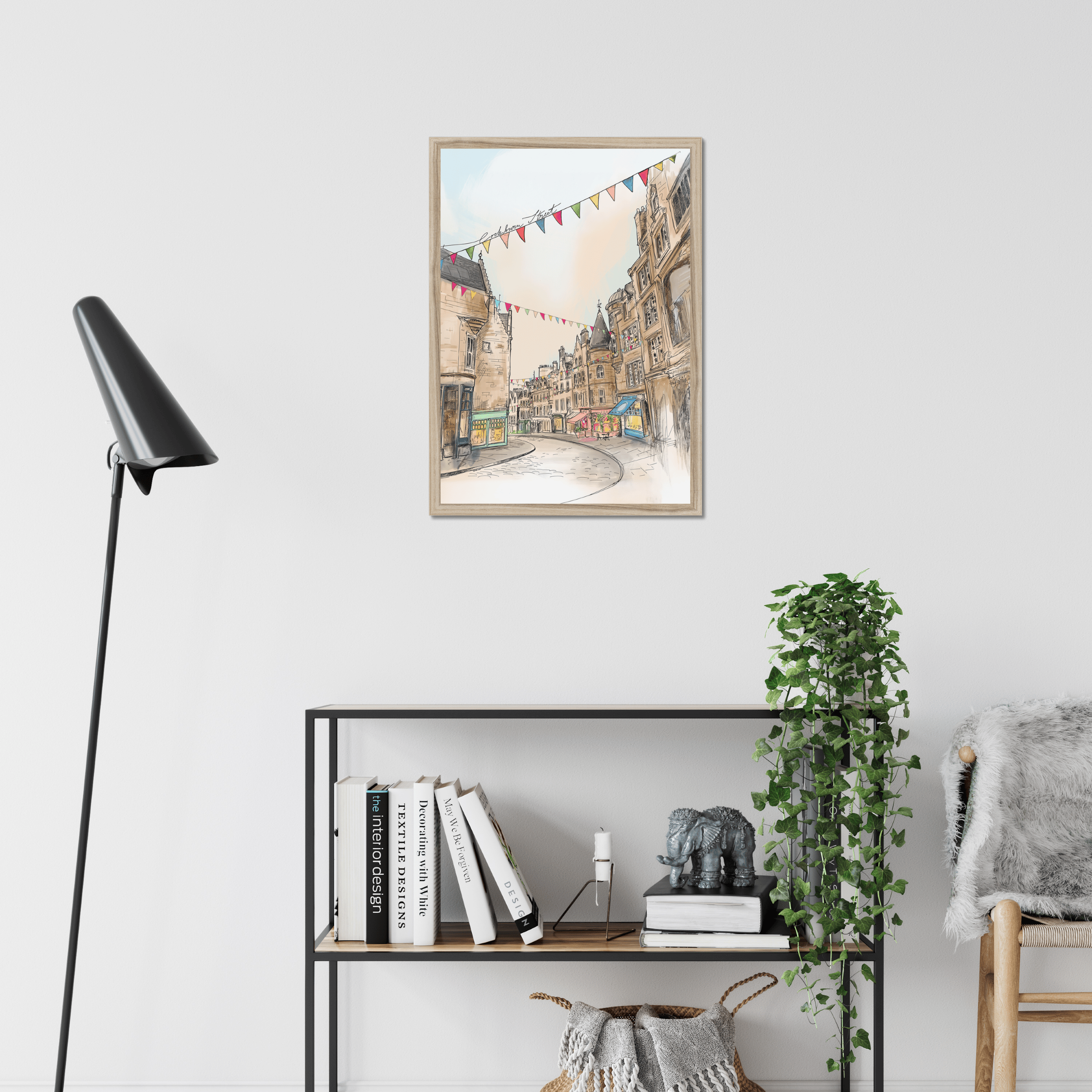 The Cockburn Street Edinburgh Matte Art Print by Essential Edinburgh is displayed in a modern room, hanging above a shelf with books, a plant, and decor. Its illustration captures the charm of the famous street known for its indie shops.