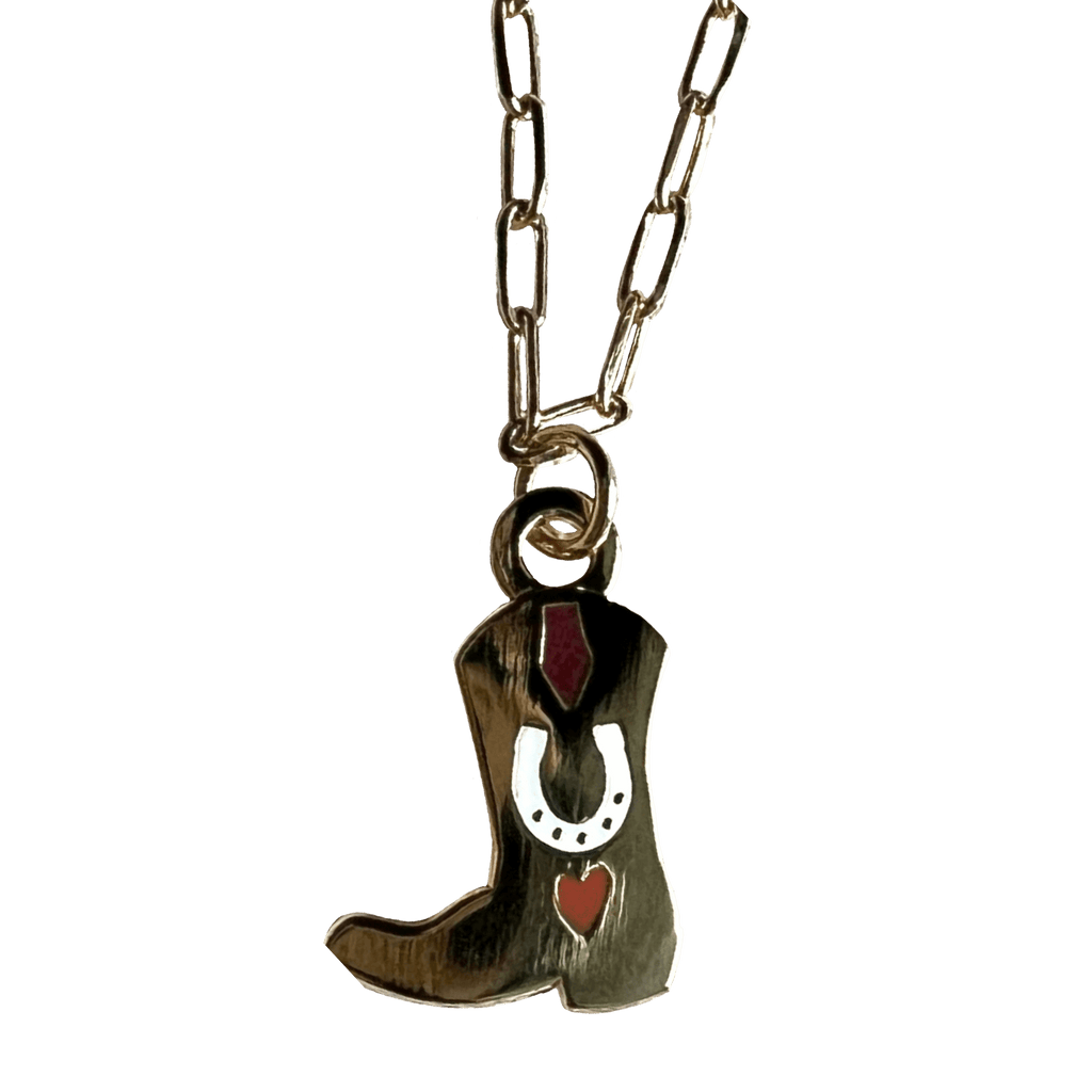 The Tiny Tootin Bootin Necklace by Necklaces features a silver horseshoe with a cowboy boot pendant, highlighted by red accents and 18k gold plating.