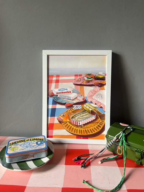The Dishy Fishy Giclée Art Print by Hôtel Dodo features a framed still life of seafood, sardine tins, and retro tableware on a red checkered tablecloth.