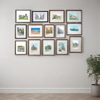 The Enchanting Edinburgh Mini Art Print Set by Essential Edinburgh features framed landscape and architectural paintings of city landmarks, arranged in a grid on a light wall above a potted plant.