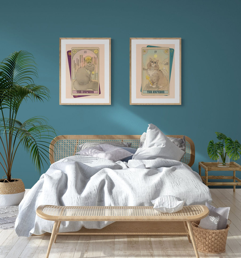 A bedroom featuring a rattan bed, white bedding, The Emperor Matte Art Print by Tarot Cats on a teal wall, potted plants, a bench, and a nightstand adds whimsy—perfect for any Tarot Cats or feline enthusiast.