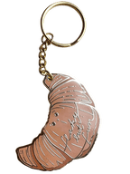 The Hôtel Dodo Kwasong Keyring features a croissant-shaped charm and an enamel tag engraved with "flaky but fun," making it a playful accessory for your keys or bag.