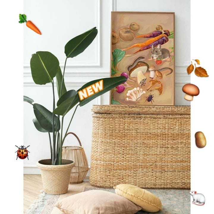 Room corner with a potted plant, wicker basket, and the colorful Earthly Delights Giclée Art Print by Kitsch Kanaveral, featuring charming vegetables and animals. Decorative elements include a ladybug, mushrooms, a carrot, leaves, and a banner reading "NEW Earthly Delights" in celebration of the harvest festival.