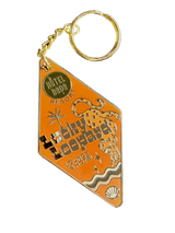 The Lucky Leopard Lounge Motel Keyring by Hôtel Dodo features a diamond-shaped enamel tag adorned with a leopard illustration, "Lucky Leopard Lounge & Hotel" text, and "Hôtel Dodo Resort," all attached to a gold keyring.