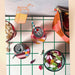 A grid surface with two soda cans on colorful coasters, a bowl of popcorn, a bowl of gummy candies, and the Hôtel Dodo Fruity Pick ‘n’ Mix Pouch made from washable fabric. An illustration of a juice box is in the background.