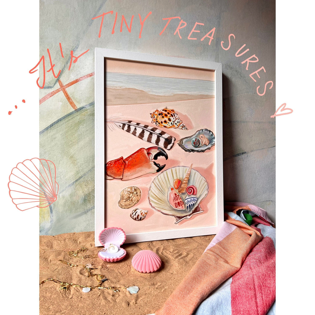 Hôtel Dodo’s Tiny Treasures Giclée Art Print features seashells, a crab claw, feathers, and sea glass on sand with pink shells, a necklace, and pastel-striped towel—ideal for anyone who loves seaside treasures.