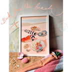 The Hôtel Dodo Tiny Treasures Giclée Art Print features a framed illustration of seashells on sand, adorned with real shells, sea glass, and a colorful towel; “Back from the beach” appears above in cursive.