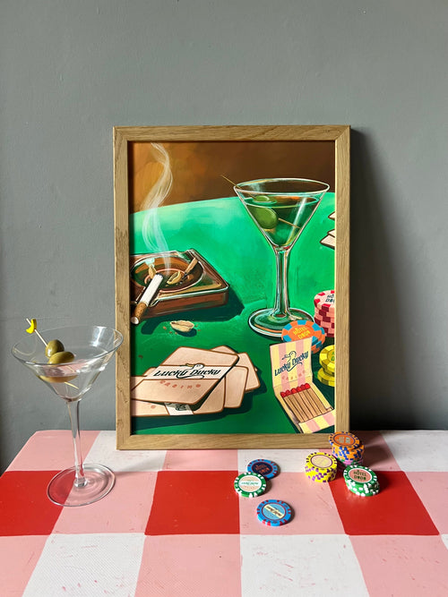 The Lucky Ducky Casino Giclée Art Print by Hôtel Dodo features a vibrant framed scene of a martini, poker chips, and cigar against a gray wall, with real chips and a martini on a red-checkered surface for added depth.
