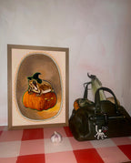 The Grumpy Spiced Pumpkin Giclée Art Print by Kitsch Kanaveral, featuring a rabbit in a witchy hat, sits beside a green bag with cat charm, corn, a mini pumpkin, and garlic on a pink checkered surface.