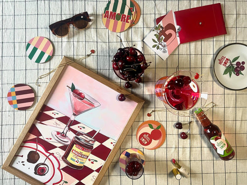 A flat lay featuring Hôtel Dodo's Cherry Bomb Giclée Art Print, drinks in glasses, coasters, sunglasses, a red purse, and a bottle—all arranged on a checkered surface like cherished finds from your mind palace.