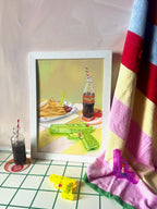 The Chlorine Cowboys Giclée Art Print by Hôtel Dodo features fries, cherries, and a cola bottle on a table with toy water guns and a towel—each detail capturing carefree summer memories.