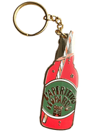 The Hôtel Dodo Aperitivo Keyring features a gold leopard and an enamel charm shaped like a red vintage soda bottle labeled "Aperitivo Leopardo," topped with a striped straw—a playful accessory for your bag.