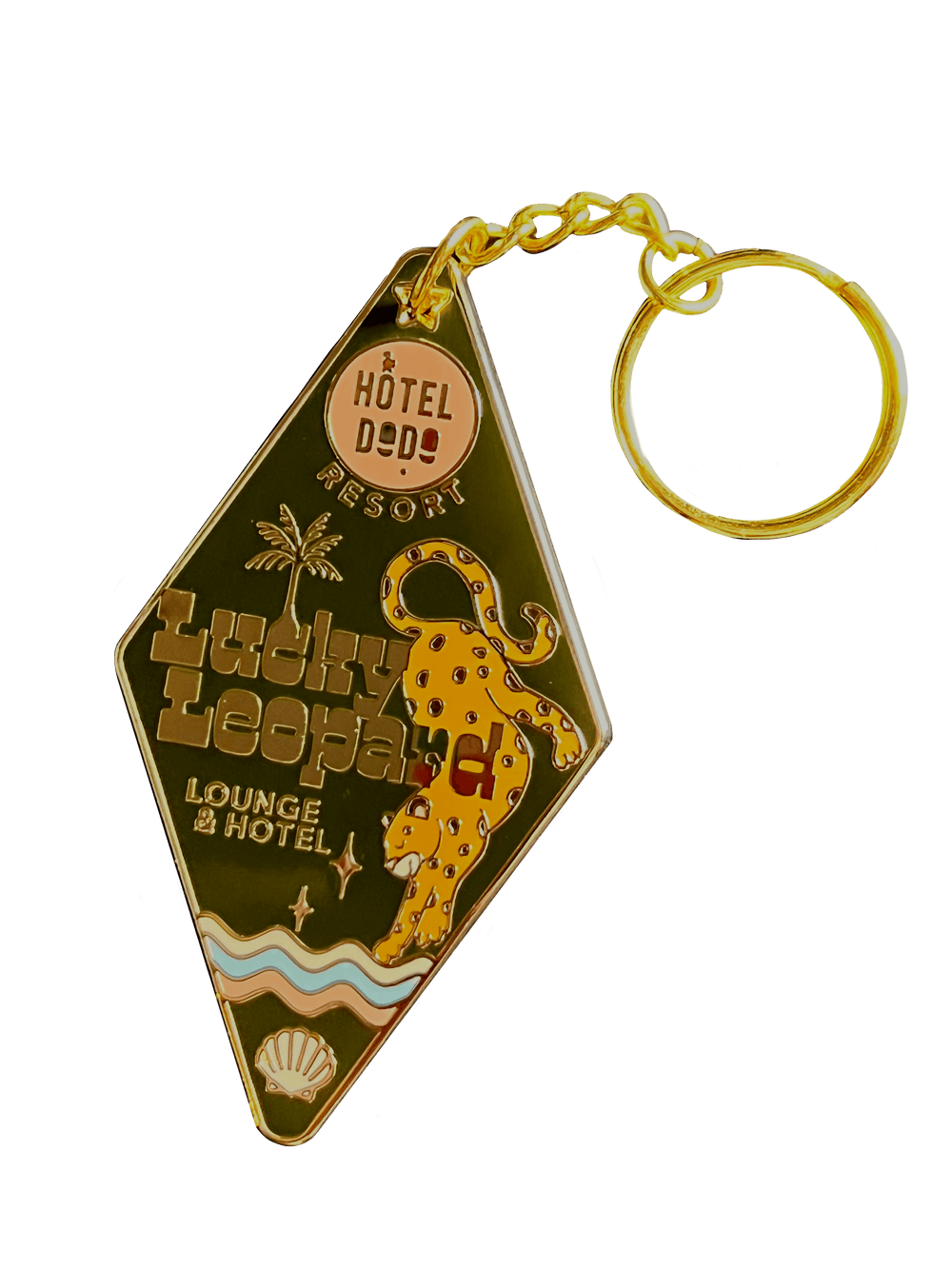 A diamond-shaped enamel tag from Hôtel Dodo features a golden leopard and the text "Lucky Leopard Lounge Motel," along with a seashell icon.