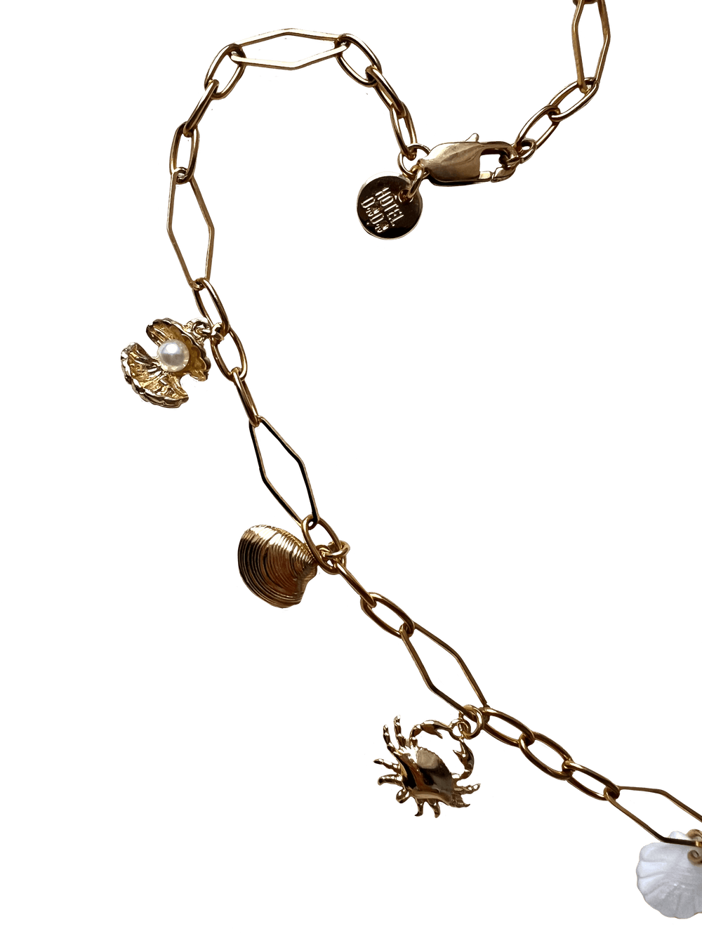 The Seaside Treasures Necklace by Necklaces, featuring gold-plated seashell charms including a crab, a shell, and a circular pendant with text, set against a black background.