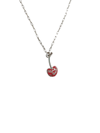 The Mon Chérie Necklace by Necklaces is a small paperclip chain featuring a red heart-shaped pendant pierced by an arrow with "Mwah" inside, elegantly set against a black background.