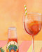 A glass of iced aperitif adorned with an orange slice and paper straw sits beside a bottle labeled "L'Aperitivo," capturing the essence of a fruity Indian summer picnic. The scene is set against a gradient backdrop of warm orange and yellow hues, evoking an idyllic evening ambiance reminiscent of Hôtel Dodo's L'Aperitivo Leopardo Giclée Art Print.