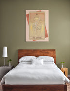 A wooden bed with white bedding sits against an olive-green wall, above which hangs The Lovers Canvas Print by Tarot Cats, featuring tarot-inspired cat artwork.