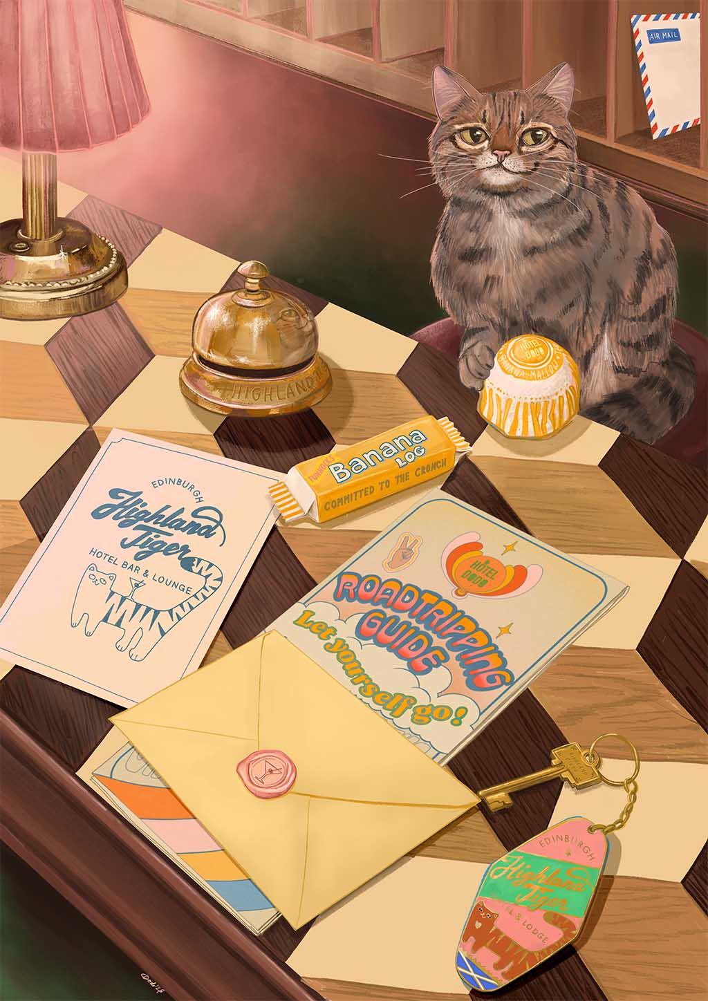 A tabby cat sits on a checkered desk surrounded by stationery, a quirky keychain, a yellow envelope, a candy bar, a cupcake, helpful travel guides titled “Road Tripping Guide” and “Edinburgh Trip,” and the Highland Tiger Lodge Giclée Art Print from Hôtel Dodo.