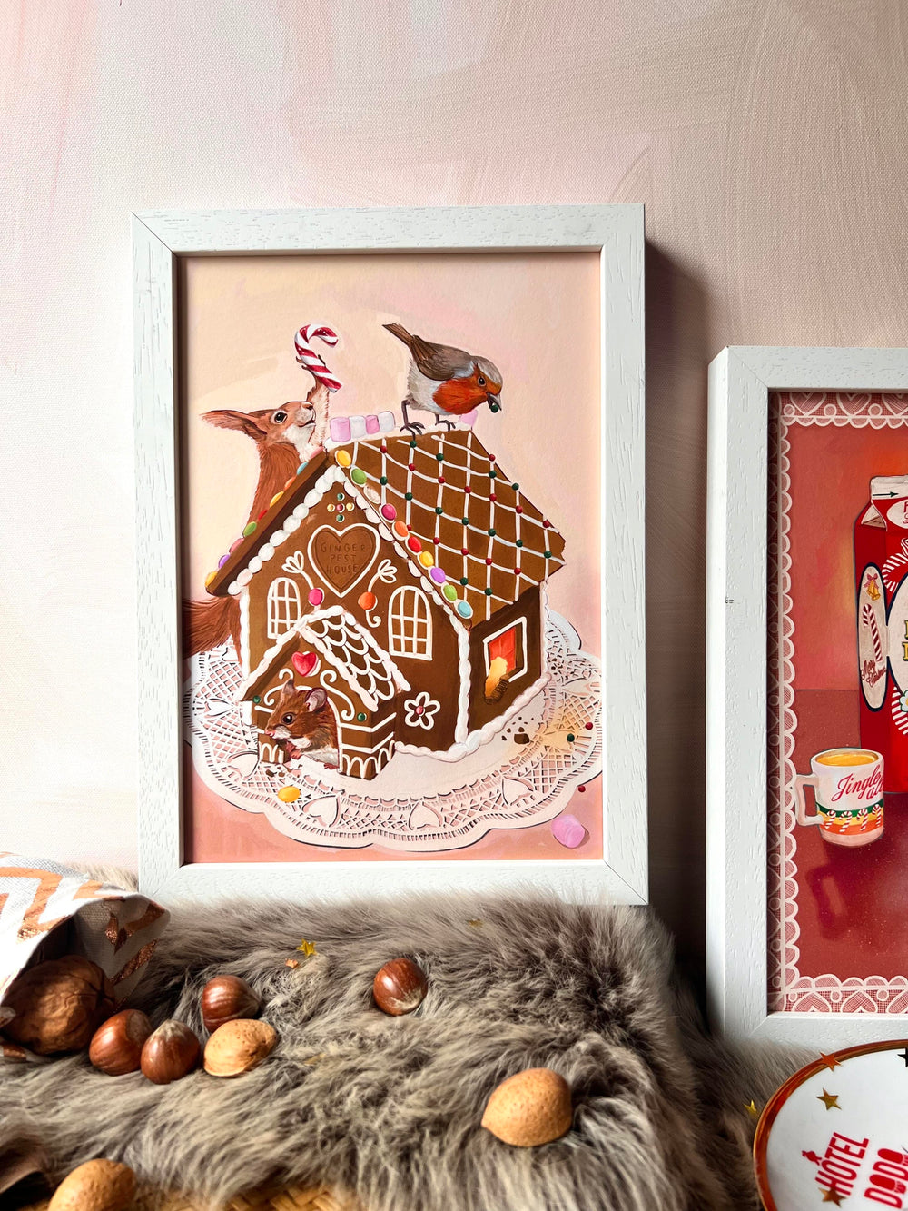 The Gingerpest House Giclée Art Print by Kitsch Kanaveral features a gingerbread house artfully illustrated with a deer and a bird, surrounded by nuts and presented on a fluffy surface.