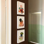 Three Catastract Tangerine Tiger Matte Art Prints hang vertically on a brown hallway wall, beside a partially open door and a green-accented wall, adding subtle beachy holiday vibes.