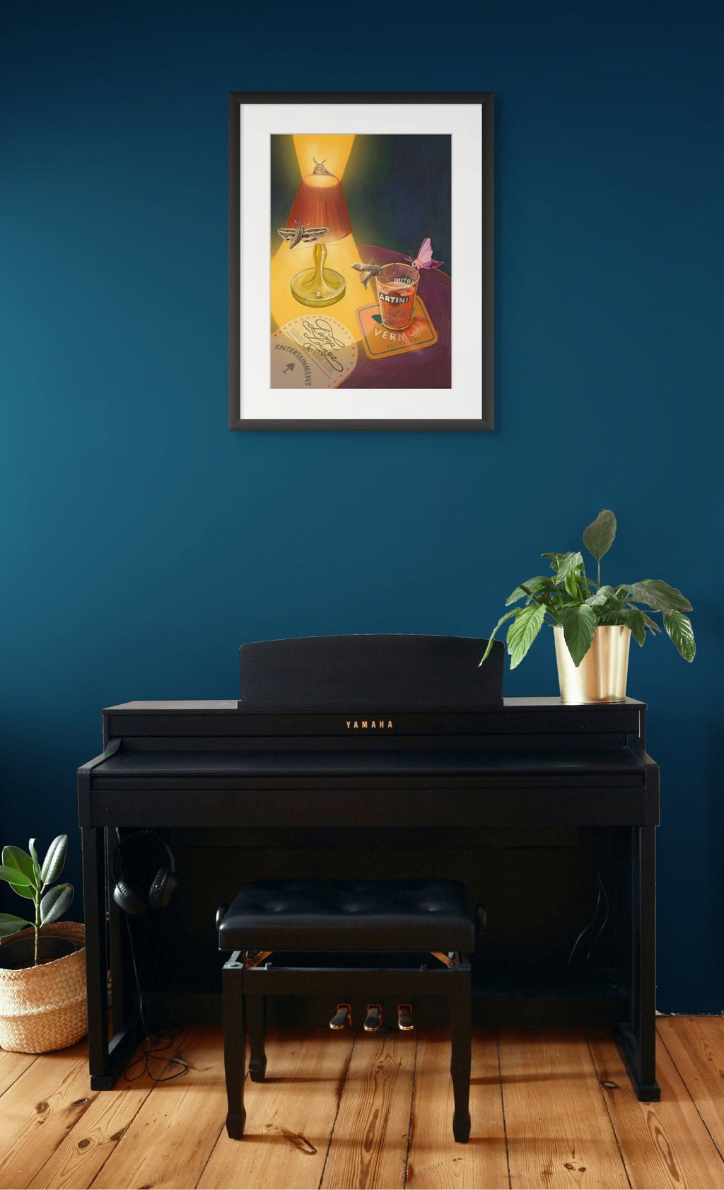 A black Yamaha digital piano with a matching bench sits against a blue wall, topped with potted plants. Above it hangs Hôtel Dodo's Lamp Lounge Giclée Art Print—evoking the ambiance of the iconic venue.