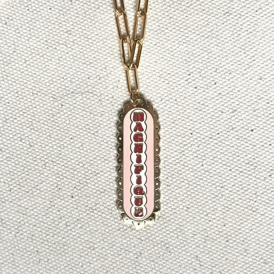 Vintage gold-toned Magnifique Necklace with a medium paperclip chain and a rectangular scalloped pendant featuring an edge with a pink inset and silver lettering by Necklaces.